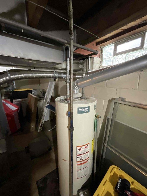 Provided estimate for new tankless water heater installation to replace existing non-functional 50-gallon standard natural draft unit in basement utility area. Assessed current plumbing configuration, venting requirements, and gas line capacity to determine specifications for tankless conversion. Documented existing Reliance water heater location, surrounding piping layout, and available space for proper tankless unit installation and code-compliant venting modifications.