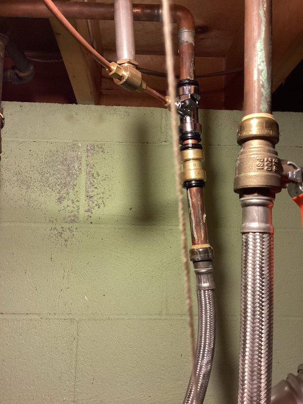 Completed routine Air Care Heating and Cooling maintenance inspection. Inspected and documented plumbing connections, water supply lines with braided stainless steel flex hoses, brass shut-off valves, copper piping, and associated mechanical components in utility area. All systems operational with photographic documentation recorded for service records.