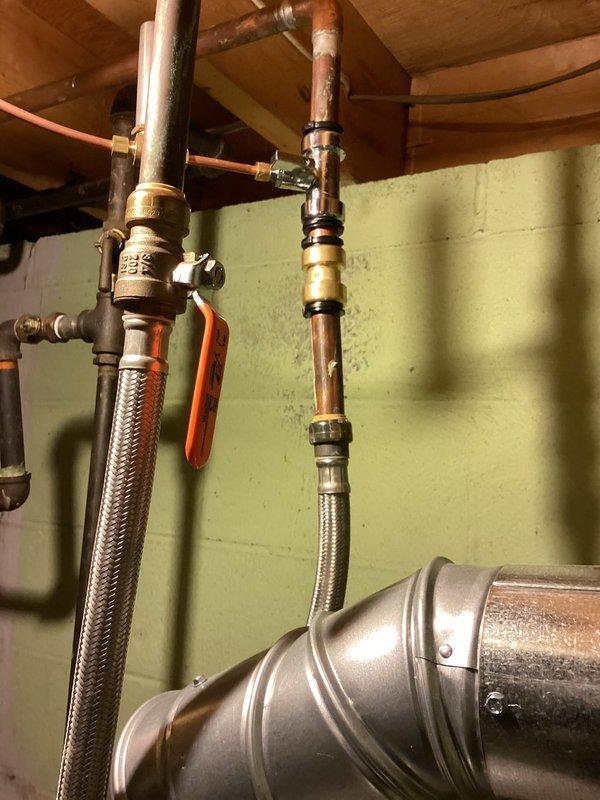 Completed routine Air Care Heating and Cooling maintenance inspection. Inspected and documented plumbing connections, water supply lines with braided stainless steel flex hoses, brass shut-off valves, copper piping, and associated mechanical components in utility area. All systems operational with photographic documentation recorded for service records.