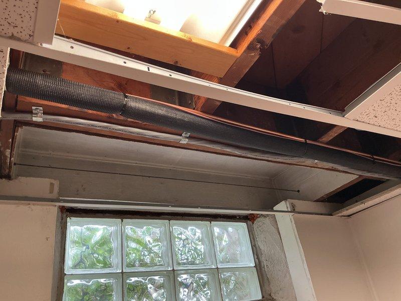 Completed full HVAC system installation including a 70,000 BTU furnace mounted in attic space with exposed copper refrigerant lines, whole-home humidifier integration, and 2-ton air conditioning condensing unit positioned on rear deck. Refrigerant line sets were properly insulated with white covering and routed vertically along exterior siding, electrical connections completed, and all components tested for proper operation.