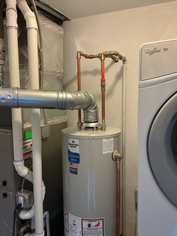 Installed a 40-gallon Bradford White residential water heater with B-vent exhaust system in utility room. Connected supply and discharge plumbing lines using brass fittings and flexible connectors, installed drain pan beneath unit, and established proper venting through existing ductwork. All mechanical connections were completed per code requirements, with permits obtained for mechanical and reconnection work.