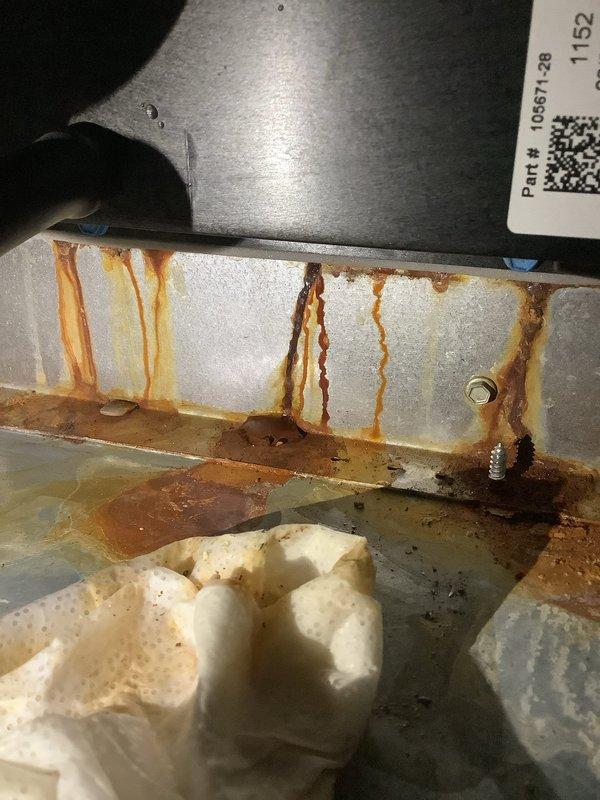 Responded to service call for thermostat experiencing WiFi connectivity issues and static display, though heating function remained operational. Upon arrival, performed diagnostic evaluation of thermostat and HVAC system. Inspection revealed significant water damage and corrosion within the air handler unit, including extensive rust staining on the drain pan and interior metal surfaces, indicating long-term moisture intrusion. The condensate drainage system showed signs of compromised integrity with standing water present in collection areas. Assessed thermostat wiring and connections for moisture exposure that could contribute to static display and connectivity problems. Documented equipment condition with photographic evidence showing deteriorated drain pan, corroded metal components, and compromised insulation material. Advised of underlying moisture issues requiring attention to prevent further equipment degradation and potential electrical complications affecting thermostat perfor