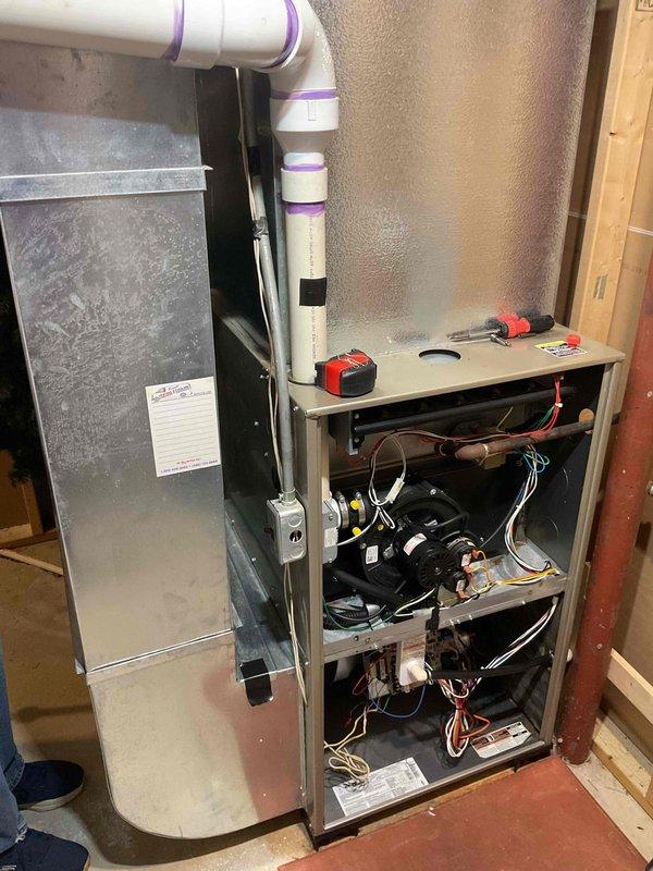 Completed comprehensive HVAC system estimate for full system replacement in basement location. Evaluated existing 10-15 year old natural gas furnace and air conditioning system, both currently operational but approaching end of serviceable life. Performed thorough assessment of stacked furnace and air handler configuration, inspecting internal components including blower motor, circuit boards, wiring harness, and control systems. Documented existing PVC condensate drain line routing and ductwork connections including curved metal plenum attachment. Evaluated utility room access, clearances, and installation requirements for new equipment. Photographed current system configuration showing furnace with upper evaporator coil cabinet, exposed basement installation with unfinished walls and concrete flooring. Assessed existing infrastructure including electrical service, gas supply line, condensate drainage system, and supply/return ductwork compatibility. Provided equipment recommendations