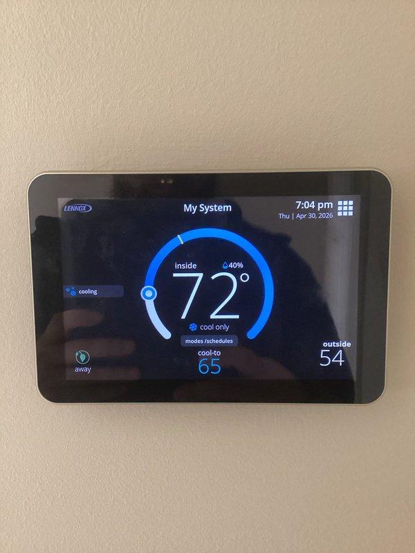 # HVAC Maintenance - ACM Completed

Performed comprehensive Air Care Cooling maintenance on Lennox residential cooling system. Conducted full system inspection of outdoor condenser unit positioned on concrete pad adjacent to building exterior. Unit found in good operating condition with no visible damage to cabinet, louvered panels, or protective top cover.

Verified thermostat operation and system controls. Lennox digital thermostat displaying proper communication with HVAC equipment, showing inside temperature of 72°F in cooling mode with setpoint of 65°F. Outside temperature reading of 54°F confirmed accurate sensor function. System actively cooling and responding appropriately to thermostat commands.

Inspected outdoor condensing unit components including cabinet integrity, louver condition, and mounting stability on concrete pad. Refrigerant lines and electrical connections examined for proper installation and absence of damage. No refrigerant leaks detected. All safety controls a