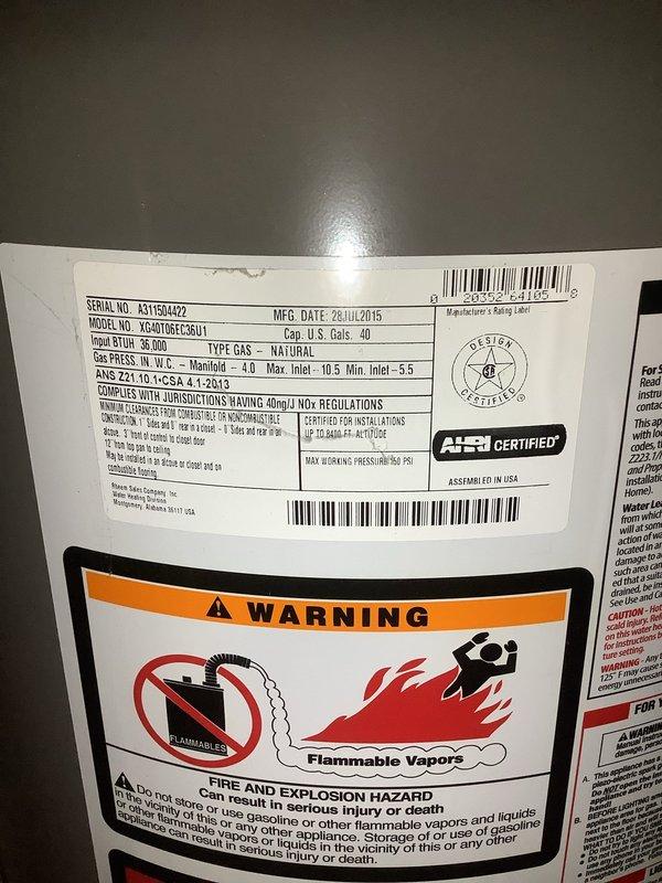 Responded to water leak complaint originating from hot water tank. Upon inspection, identified a 40-gallon natural gas water heater manufactured in July 2015 showing signs of deterioration and active leaking. Documented unit specifications including model and serial number for replacement purposes. Observed water accumulation in drain pan beneath HVAC system, indicating ongoing leak condition. Photographed water heater data plate and affected drain pan area with visible water damage and staining. Advised customer that leak indicates end of life for existing water heater and recommended replacement. Customer acknowledged condition and elected to proceed with necessary repairs.