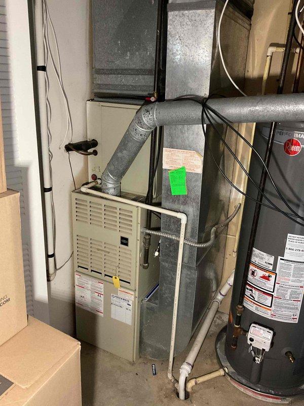 Conducted comprehensive assessment of existing residential HVAC system located in basement utility area for full system replacement estimate. Evaluated current furnace unit with flexible ductwork connections, air handler configuration, and overall mechanical room layout to determine equipment specifications and installation requirements. Documented existing system components including furnace, ductwork with visible condensation on flex piping, and spatial constraints to provide accurate recommendations for complete HVAC system replacement including new air conditioning unit and furnace installation.