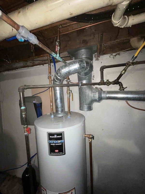 Provided comprehensive estimate for tankless water heater replacement to upgrade 15-year-old conventional tank-style unit located in basement utility area. Assessed existing natural gas-fired water heater installation, including current venting configuration through metallic ductwork, copper supply line connections, and proximity to existing sump pump system. Evaluated basement infrastructure including exposed ceiling joists, existing gas line accessibility, electrical requirements for tankless unit operation, and adequate clearances for new equipment installation and proper combustion air supply.
