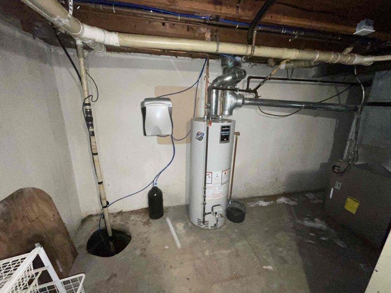 Provided comprehensive estimate for tankless water heater replacement to upgrade 15-year-old conventional tank-style unit located in basement utility area. Assessed existing natural gas-fired water heater installation, including current venting configuration through metallic ductwork, copper supply line connections, and proximity to existing sump pump system. Evaluated basement infrastructure including exposed ceiling joists, existing gas line accessibility, electrical requirements for tankless unit operation, and adequate clearances for new equipment installation and proper combustion air supply.
