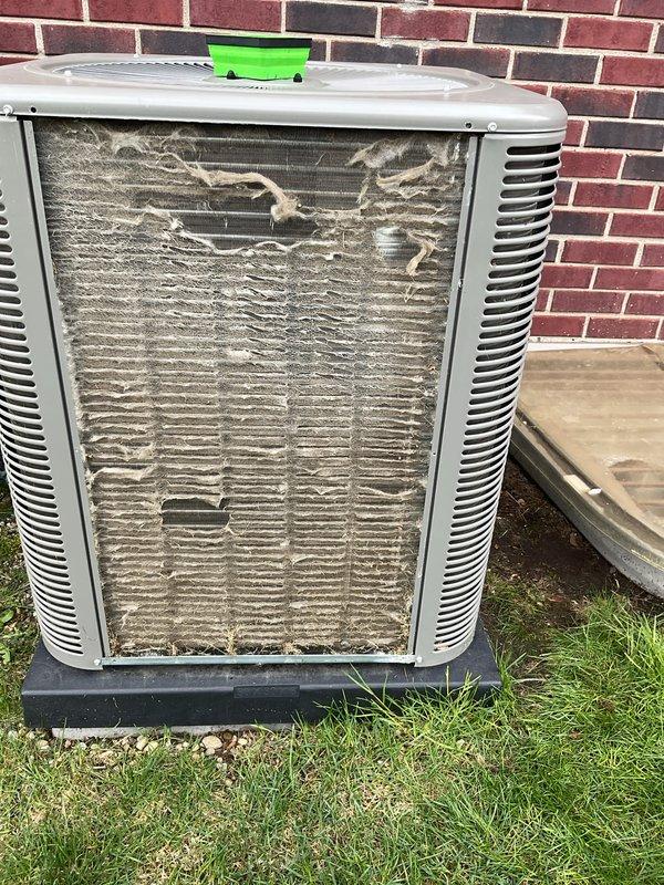 Completed annual cooling maintenance on residential split system. Unit exterior was heavily clogged with debris, dust, and fibrous material restricting airflow through condenser coils. Cleaned condenser coil and housing thoroughly to restore proper ventilation and heat exchange efficiency. Performed electrical diagnostics using digital multimeter, verifying system voltage and amperage readings within manufacturer specifications at 82.12 reading. Inspected all electrical connections and wiring harness inside unit compartment. System operational and running efficiently after cleaning and testing procedures completed.