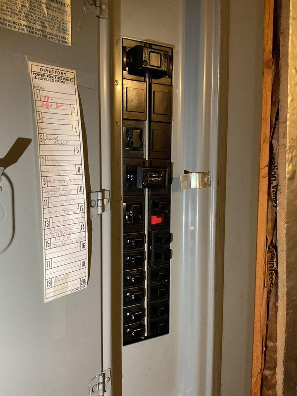 Conducted comprehensive site assessment for electrical panel upgrade in unfinished basement utility area. Evaluated existing residential distribution panel with multiple circuit breakers, documented current panel configuration and directory labeling system, and photographed installation conditions including surrounding construction elements, exposed framing, concrete block walls, and clearance access to panel location. Verified adequate workspace and accessibility requirements for proposed panel upgrade installation.