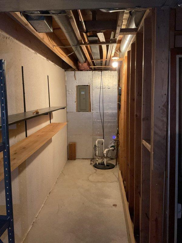 Conducted comprehensive site assessment for electrical panel upgrade in unfinished basement utility area. Evaluated existing residential distribution panel with multiple circuit breakers, documented current panel configuration and directory labeling system, and photographed installation conditions including surrounding construction elements, exposed framing, concrete block walls, and clearance access to panel location. Verified adequate workspace and accessibility requirements for proposed panel upgrade installation.