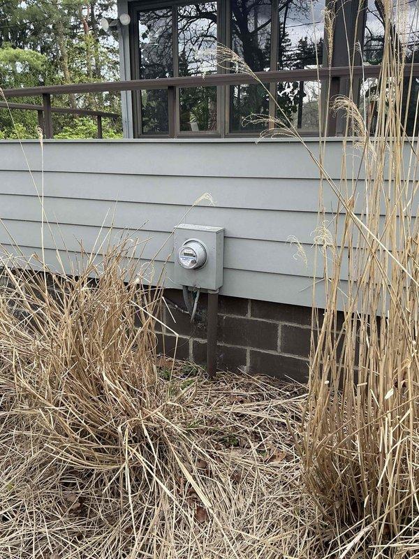 Conducted on-site evaluation for new whole home Kohler generator installation. Assessed existing electrical service panel and meter location on exterior wall with gray siding, documented current utility connections including gas line infrastructure at ground level. Evaluated optimal placement for generator unit considering clearance requirements from structure, utility access points, and existing landscaping. Photographed electrical meter configuration and gas service entry point to determine connection routing and necessary materials for installation. Prepared comprehensive estimate for complete generator system including automatic transfer switch, fuel line connection, concrete pad placement, and electrical integration with main service panel.