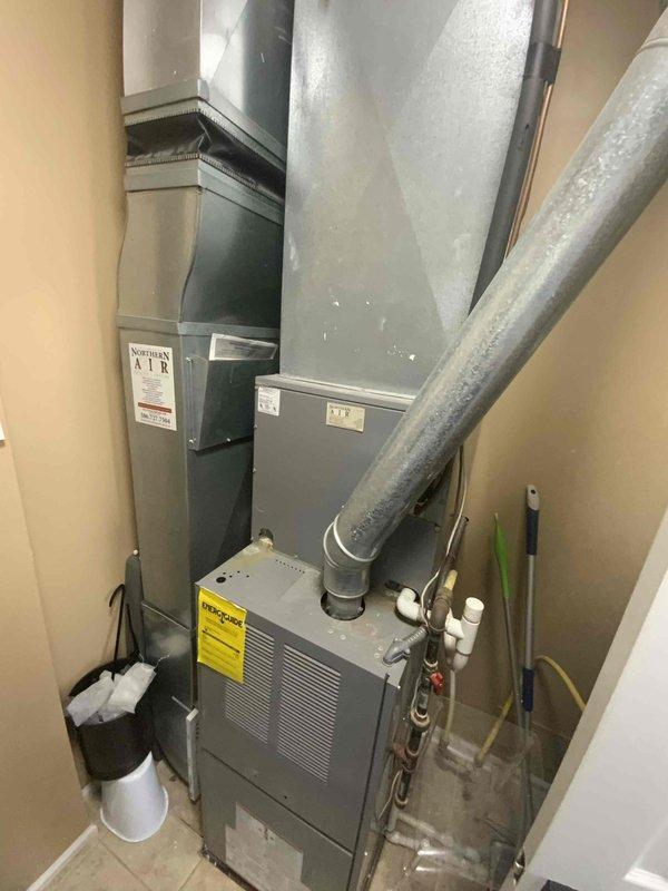Provided estimate for BOGO furnace and air conditioning replacement in utility closet of split system condo. Existing air conditioning unit is non-operational and equipment is aged beyond serviceable life. Assessment included evaluation of current vertical installation configuration with gray metal furnace, air handler, and associated ductwork including rigid metal and flexible insulated ducts, along with electrical panel capacity for new system installation.