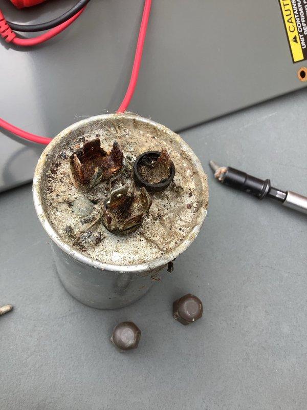 Completed scheduled air conditioning maintenance on outdoor condensing unit. Upon inspection, discovered heavily corroded dual-run capacitor with severe rust damage to terminals and extensive mineral buildup on casing, indicating electrical component failure due to moisture exposure. Replaced failed capacitor with new unit. Removed debris, twigs, and organic material from equipment compartment that had accumulated from outdoor exposure. Cleaned electrical connections and terminal points. Inspected wiring and conduit for damage. Unit tested and operational following component replacement and cleaning.