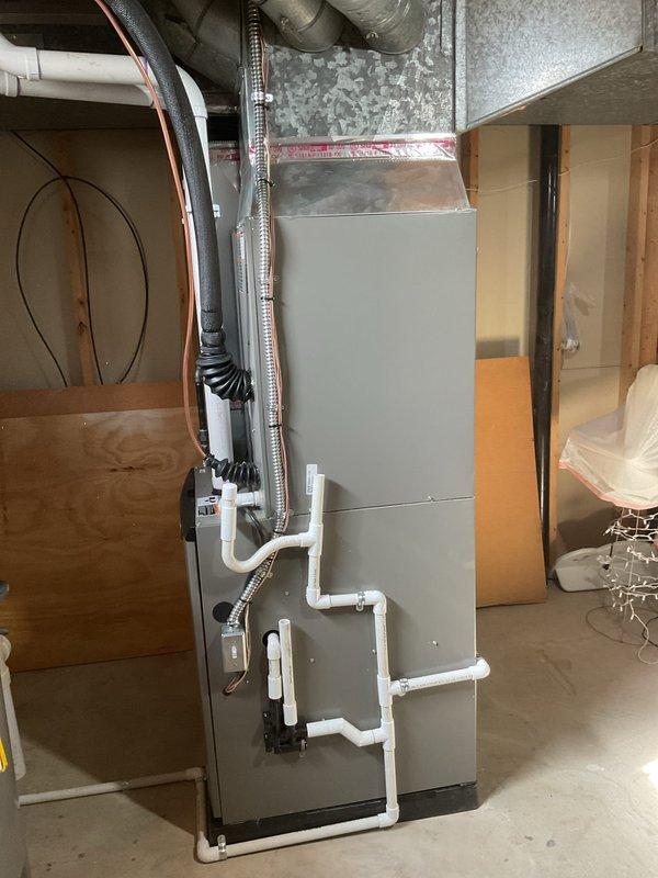 Completed full HVAC system replacement including installation of 90,000 BTU furnace and 3-ton air conditioning unit with rear discharge configuration. Installed furnace in basement utility area with new PVC condensate drain lines, flexible metal supply ductwork, and copper refrigerant line set connected to existing ductwork system. Mounted outdoor condenser unit on concrete pad against exterior brick wall with proper refrigerant line routing, electrical disconnect box, and line set brackets for secure copper tubing installation. Reconnected all electrical and mechanical connections, verified proper system operation, and ensured installation met mechanical permit requirements.