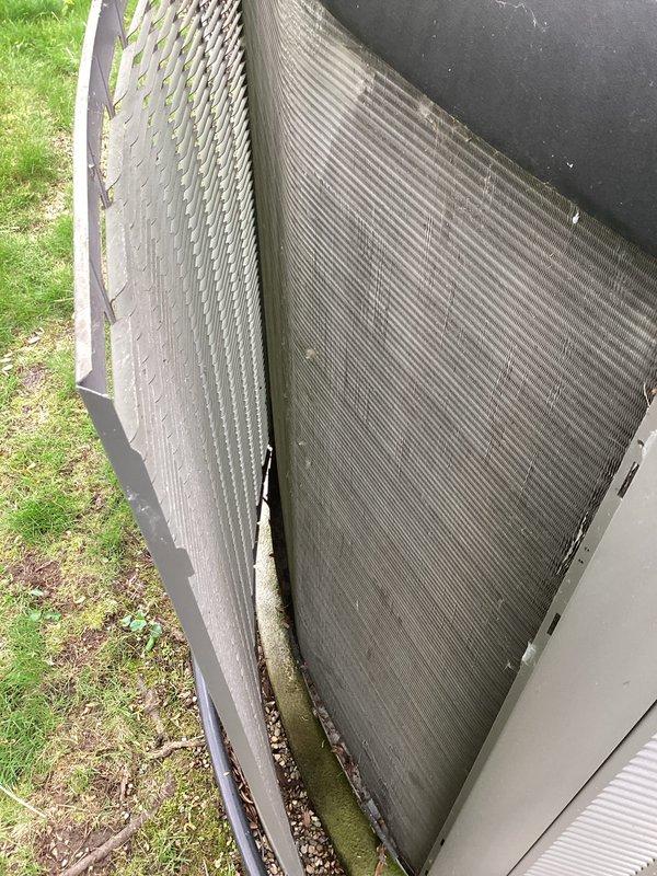 Completed annual Air Care Cooling maintenance inspection on outdoor condensing unit. Unit exterior showed moderate accumulation of dirt, debris, and organic matter on condenser coil fins and cabinet panels, with visible moss growth along lower sections indicating extended environmental exposure. Documented equipment condition with photos showing fin integrity maintained despite debris buildup, performed standard 10-year recurring service protocol including visual assessment of all accessible components.