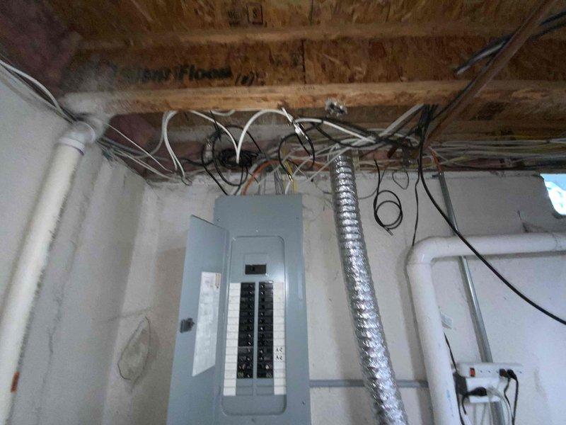 Completed electrical estimate for new whole home generator installation at manufactured home residence. Assessed existing electrical panel configuration in basement utility area, documented current circuit breaker layout serving kitchen, bathrooms, bedrooms, garage, pool equipment, and HVAC systems. Evaluated electrical infrastructure including panel capacity, wiring routes through ceiling joists, and available space for generator transfer switch integration to determine installation requirements and feasibility for backup power system.