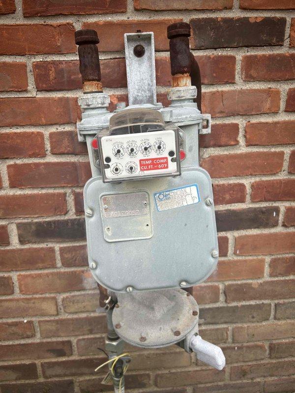 Performed site evaluation for new tankless water heater installation with natural draft venting configuration. Assessed existing gas meter infrastructure and utility connections on exterior brick wall to determine compatibility and capacity requirements for tankless unit upgrade. Documented current gas supply system condition and specifications to prepare comprehensive estimate for complete tankless water heater installation.