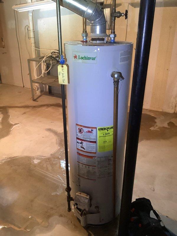 Responded to urgent service call for Lochinvar tanked water heater experiencing leaks from top and side connections with complete loss of hot water supply. Upon inspection, identified active water leakage causing moisture damage on basement concrete floor. Performed diagnostic evaluation of tank integrity, inlet/outlet connections, temperature and pressure relief valve, and all associated plumbing connections to determine source of failure and assess whether repair or replacement was most appropriate solution.