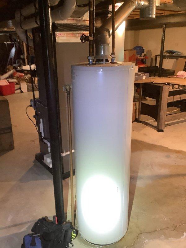 Responded to urgent service call for Lochinvar tanked water heater experiencing leaks from top and side connections with complete loss of hot water supply. Upon inspection, identified active water leakage causing moisture damage on basement concrete floor. Performed diagnostic evaluation of tank integrity, inlet/outlet connections, temperature and pressure relief valve, and all associated plumbing connections to determine source of failure and assess whether repair or replacement was most appropriate solution.
