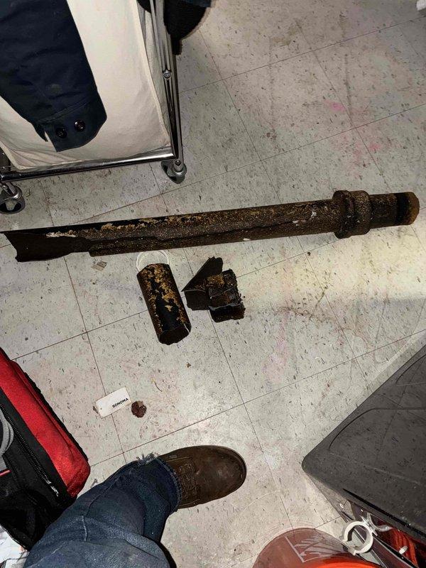 Responded to water leak investigation at residential property. Upon inspection, identified severely corroded cast iron drain piping at ceiling level in basement utility area, connected to white PVC vertical stack via coupling joint. Extensive rust and deterioration observed on horizontal cast iron section, indicating advanced age and compromising pipe integrity. Removed deteriorated piping sections, which exhibited heavy corrosion throughout with significant material degradation. Provided comprehensive assessment and quote for necessary repairs to address leak source and prevent future water damage.