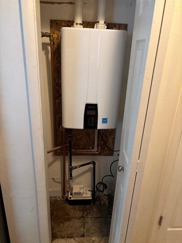 Completed installation of Energy Star certified wall-mounted tankless water heater in interior utility closet with new electrical circuit and dedicated disconnect. Installed white PVC venting system through exterior wall, connected gas supply lines, and integrated expansion tank with black piping configuration. Simultaneously installed outdoor air conditioning condenser unit on gravel pad with proper refrigerant line connections, electrical disconnect box mounted to exterior siding, and conduit run through vinyl siding. All mechanical and electrical permits obtained prior to installation, system tested and verified operational upon completion.