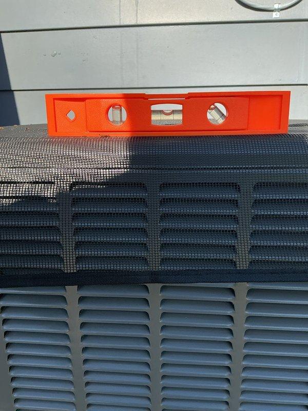 Responded to service callback regarding unlevel air conditioning unit following recent installation of 70,000 BTU furnace and 2-ton rear-discharge AC system. Verified unit levelness using precision spirit level on top of condenser cabinet and documented measurements with photographs. Made necessary adjustments to ensure proper equipment leveling for optimal operation and drainage.