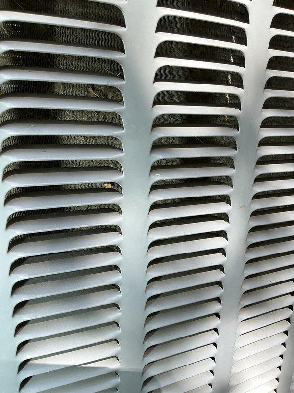 Completed annual preventative maintenance on HVAC system. Inspected and photographed evaporator coil fins and ventilation grilles, noting dust accumulation on upper louvers. Verified proper airflow through heat exchanger components and documented condition of condenser coils across all three columns for maintenance records.