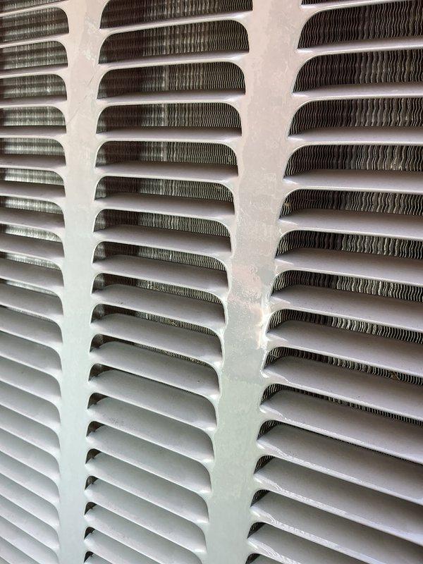 Completed annual preventative maintenance on HVAC system. Inspected and photographed evaporator coil fins and ventilation grilles, noting dust accumulation on upper louvers. Verified proper airflow through heat exchanger components and documented condition of condenser coils across all three columns for maintenance records.
