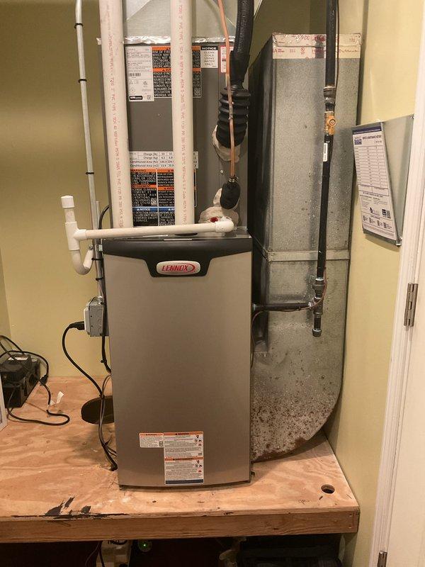 Completed full HVAC system installation including a Lennox 70,000 BTU furnace and 2.5-ton air conditioning unit with rear discharge configuration. The furnace was mounted on a wooden platform in the utility room with proper ductwork connections, PVC condensate drainage, and electrical supply established. The outdoor AC condenser was positioned on a concrete pad against the exterior wall with refrigerant lines run vertically along the siding and secured with mounting brackets. All mechanical and electrical permits were obtained prior to installation, and the system was reconnected and commissioned to manufacturer specifications.