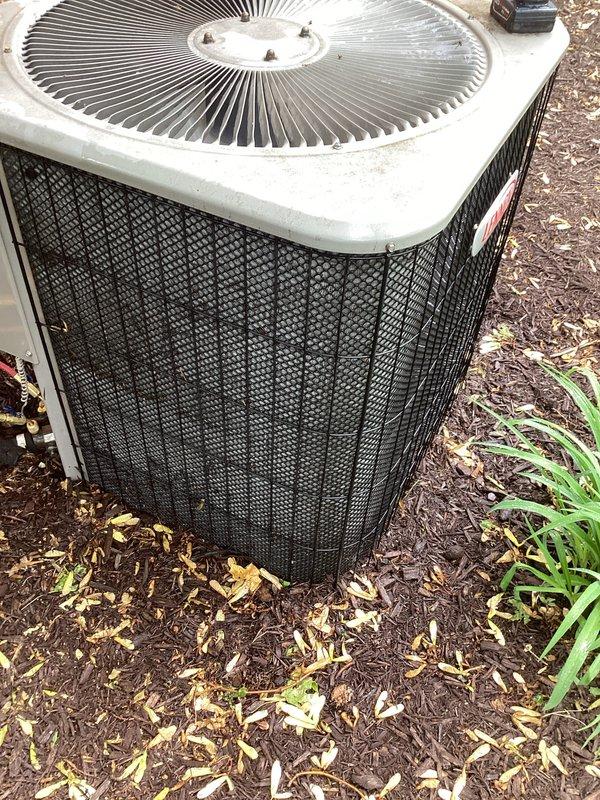 Completed annual cooling maintenance on residential outdoor air conditioning condenser unit. Performed comprehensive system inspection, documenting unit condition with photographic records showing beige cabinet with cylindrical fan assembly, protective mesh grilles, and electrical conduit connections. Unit operational with normal wear consistent with outdoor exposure; mulch and debris cleared from perimeter to maintain proper airflow clearance.