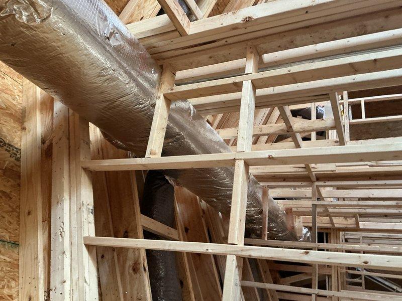 Responded to callback for HVAC installation inspection where disconnected ductwork was found hanging in chase area. Reconnected and properly secured flexible ductwork to framing members, then installed missing fire stop material around duct penetrations through floor joists to meet code requirements. Documented all corrections with photos showing insulated vertical duct run properly supported and fire-rated sealing in place.