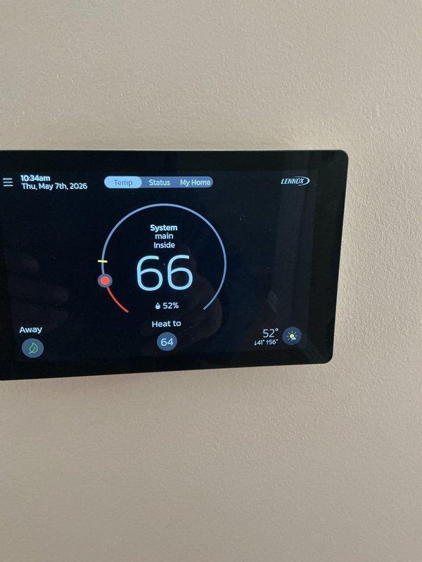 Completed scheduled air conditioning maintenance service on Lennox system. Inspected evaporator coil assembly which showed significant dust and debris accumulation on the honeycomb mesh surface, requiring attention. Replaced dirty air filter and evaporator pads per maintenance protocol. Verified thermostat operation displaying 66°F indoor temperature with system set to heat mode at 64°F target and 52% humidity level. System operational upon completion of maintenance tasks.