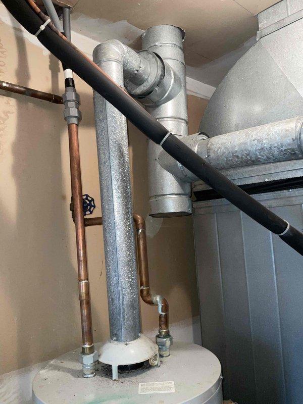 Provided estimate for replacement of existing standard tank-type water heater located in furnace room mechanical space. Current unit is operational but experiencing active leak, requiring replacement to prevent water damage and restore system integrity. Assessed installation area with existing copper supply lines, shut-off valves, and pressure relief valve configuration alongside HVAC ductwork and ventilation components in confined utility space.