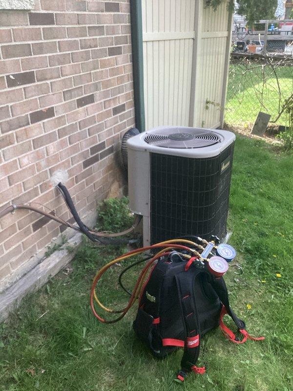 # HVAC Service Call - Air Conditioning System

Responded to service call for outdoor Amana air conditioning unit not cooling. Upon arrival, located condensing unit on concrete pad against exterior brick wall. Connected manifold gauge set to service ports to assess system pressures and diagnose cooling failure.

Performed visual inspection of condensing unit exterior condition, checking for obvious signs of damage, debris blockage in coil fins, or electrical issues at disconnect. Verified power supply at adjacent electrical meter and disconnect box. Evaluated compressor operation and fan motor function during diagnostic testing.

Measured refrigerant pressures on both high and low side of system using calibrated HVAC gauges to determine if system had adequate refrigerant charge or potential leak. Assessed temperature differential and system performance indicators to identify root cause of cooling deficiency. Equipment age noted as older with unknown service history, requiring thorough e