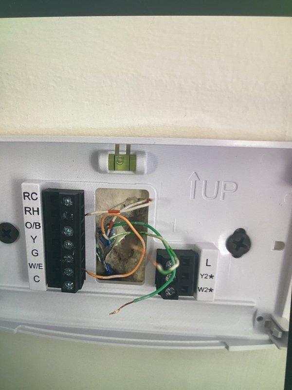 Responded to recall for A/C system not turning on or cooling, along with ongoing furnace heating issues where unit stops running before reaching setpoint. Inspected thermostat wiring and control panel connections, verifying proper wire terminations at RC, RH, O/B, Y, G, W/E, and C terminals. Examined wire connections within HVAC equipment control panel, checking all wire nuts and electrical connections for secure contact. Documented wiring configuration and thermostat interface to ensure proper communication between components and resolve intermittent operation issues affecting both cooling and heating functions.