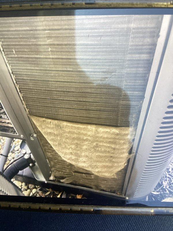 Completed scheduled Air Care Maintenance on residential HVAC system. Inspected condenser coil and heat exchanger assembly, noting moderate dust and environmental debris accumulation on exterior fins with visible discoloration on lower sections. Replaced air filter and documented unit condition with photographic evidence showing typical outdoor wear patterns on coil surfaces.