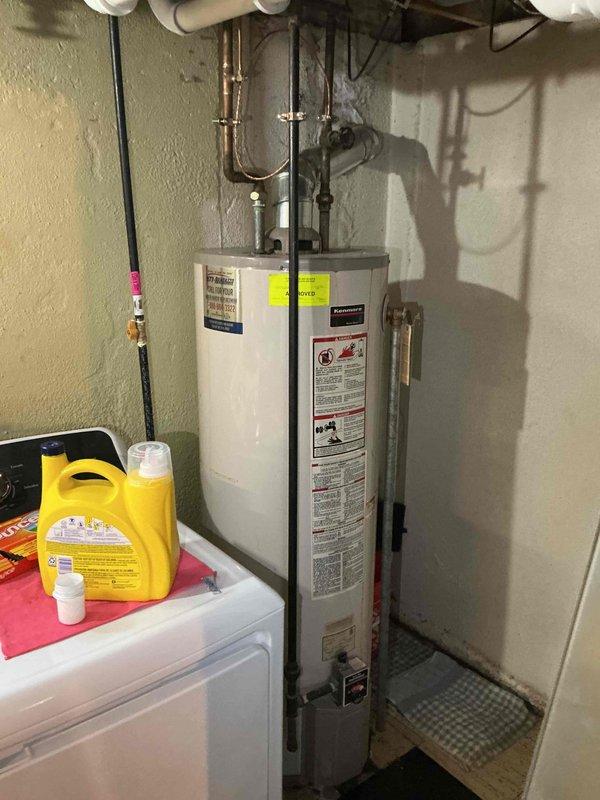 Conducted water heater replacement estimate for 30-year-old natural gas unit located in basement utility area. Assessed existing installation including copper and PVC piping connections, venting configuration, and equipment accessibility in shared space with laundry appliances. Documented current system condition and provided replacement options for aging equipment that has exceeded typical service life expectancy.