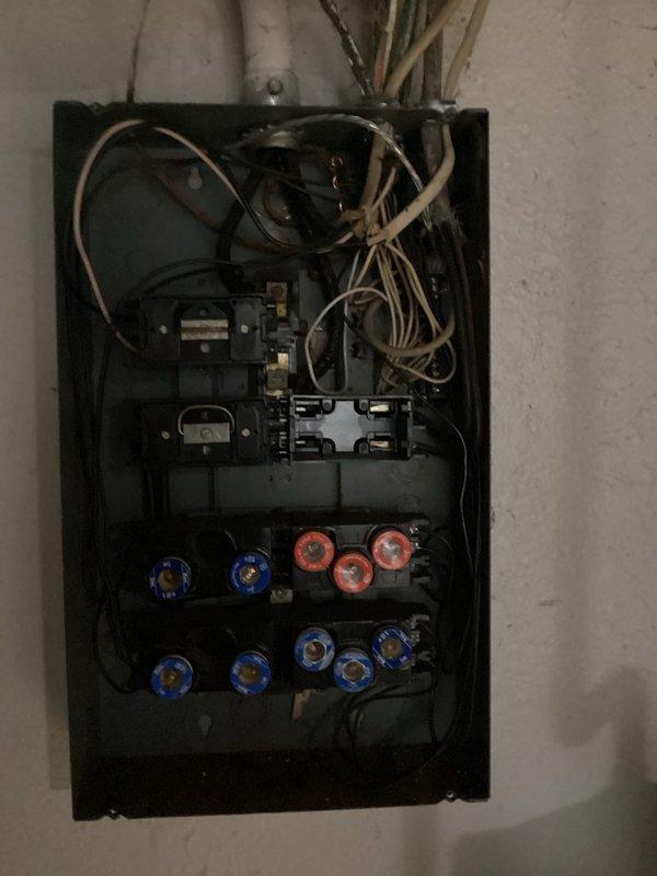 Conducted electrical panel estimate for residential property with outdated fuse-style panel experiencing multiple power outages affecting random outlets and lighting circuits throughout home. Documented existing panel condition, photographed obsolete circular fuse system with mixed fuse ratings, and assessed wiring configuration to determine scope of necessary electrical service upgrade to modern circuit breaker panel for improved safety and reliability.