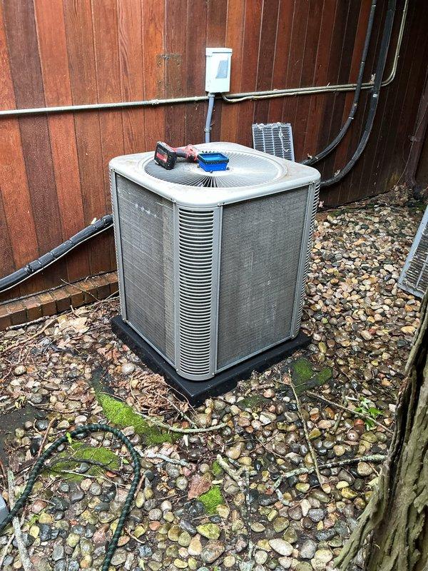 Completed comprehensive ComfortGuard maintenance service on outdoor condensing unit, performing standard preventive maintenance procedures including coil cleaning, electrical connection inspection, and system performance verification. Unit exterior showed weathering with paint deterioration on cabinet panels; cleared debris accumulation from surrounding pad area including leaves and organic matter, and addressed moss growth on concrete pad and stone base. All system components tested and confirmed operational within manufacturer specifications.