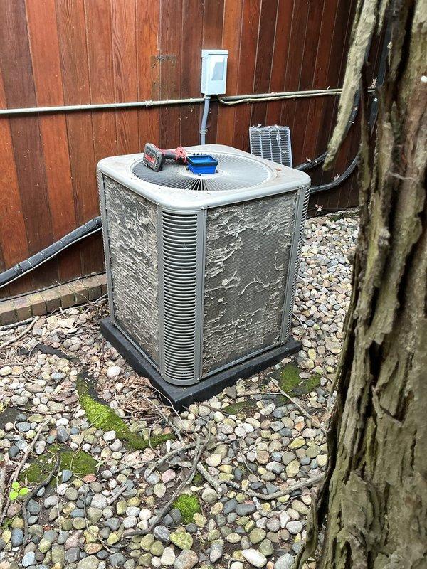 Completed comprehensive ComfortGuard maintenance service on outdoor condensing unit, performing standard preventive maintenance procedures including coil cleaning, electrical connection inspection, and system performance verification. Unit exterior showed weathering with paint deterioration on cabinet panels; cleared debris accumulation from surrounding pad area including leaves and organic matter, and addressed moss growth on concrete pad and stone base. All system components tested and confirmed operational within manufacturer specifications.
