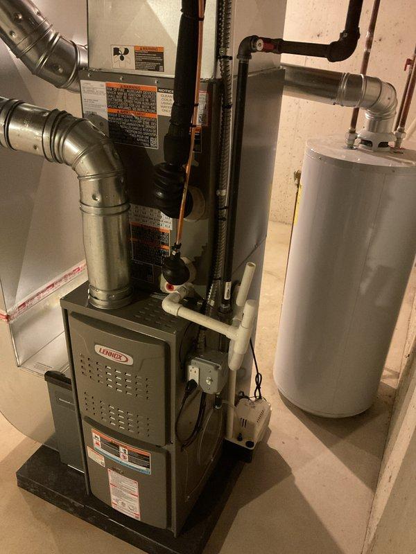 Completed full HVAC system installation in residential basement including 70,000 BTU furnace and 2.5-ton air conditioning unit with front-discharge configuration. Installed furnace on platform with proper venting and ductwork connections, mounted evaporator coil assembly above furnace with metallic supply ductwork and elbow transitions to existing distribution system. Reconnected all electrical components, established refrigerant lines to outdoor condensing unit, and verified proper drainage connections. Mechanical and electrical permits obtained prior to installation. System tested and operational upon completion.
