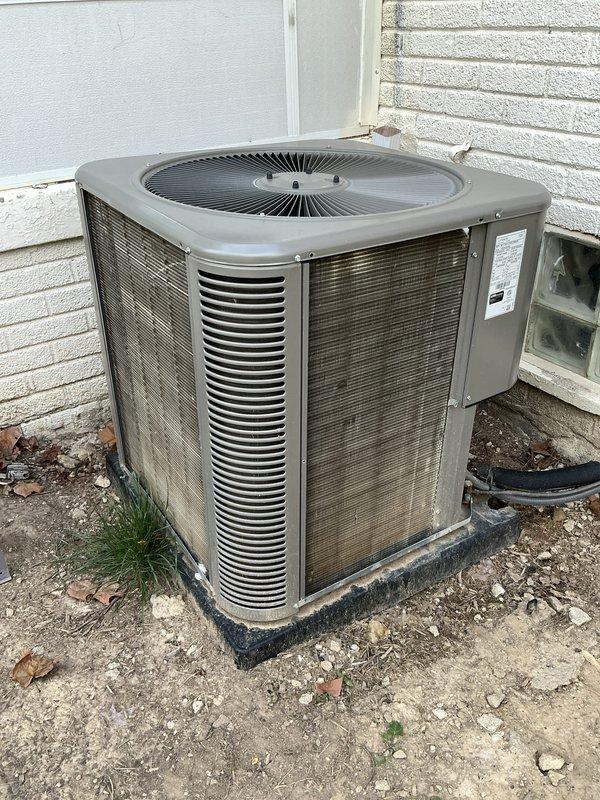 Completed scheduled maintenance on residential air conditioning system. Performed comprehensive inspection of outdoor condenser unit, noting weathered housing and accumulated debris around base. Cleaned condenser coils showing significant dirt accumulation and discoloration on heat exchanger fins. Replaced air filter per maintenance protocol. Verified unit operation and airflow through louvered panels and fan assembly. Equipment operational upon completion.