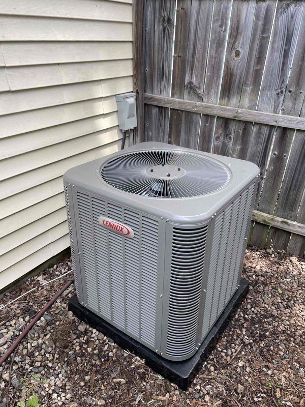 Completed installation of 2.5-ton Lennox air conditioning condenser unit and evaporator coil system at residential property. Outdoor condenser positioned on rubber isolation pad in rear yard location with proper clearance from fence and structure, electrical disconnect installed on exterior wall, and refrigerant lines connected. Indoor evaporator coil installed in basement area with existing furnace system, all ductwork connections completed, and system tested for proper operation and refrigerant charge.