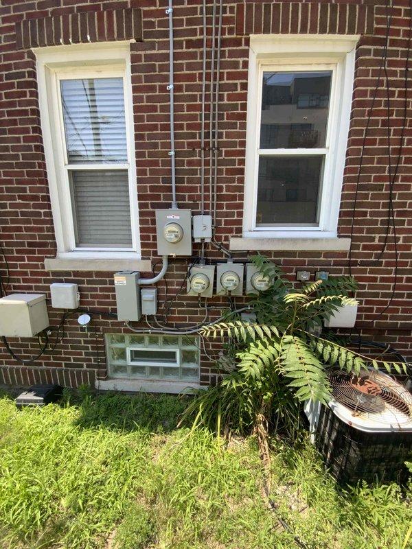 Completed HVAC system evaluation for residential replacement estimate at return customer's different apartment unit. Assessed aging outdoor condenser unit positioned against brick exterior, noting weathered condition with visible dirt accumulation and overgrown vegetation obstructing proper airflow around base of equipment. Documented existing electrical service configuration including meter location, panel access, and conduit routing for replacement planning purposes. Photographed current equipment placement, clearance requirements, and utility connections to provide comprehensive assessment for full system replacement proposal.