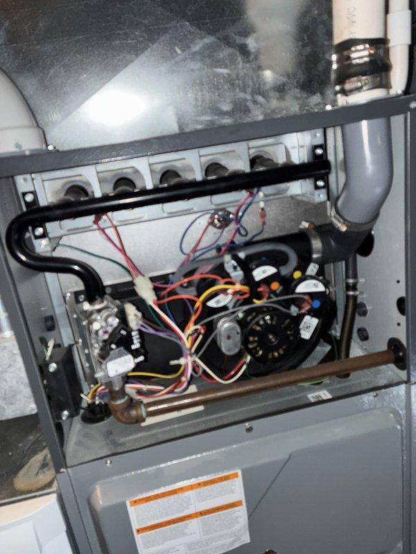Conducted on-site assessment for air conditioner replacement at residential property. Performed visual inspection of existing HVAC system including gas furnace with exposed internal components showing blower motor assembly, burner elements, and electrical connections. Documented current equipment configuration in basement mechanical room housing furnace unit and water heater with associated ductwork and PVC piping systems to prepare comprehensive replacement estimate.