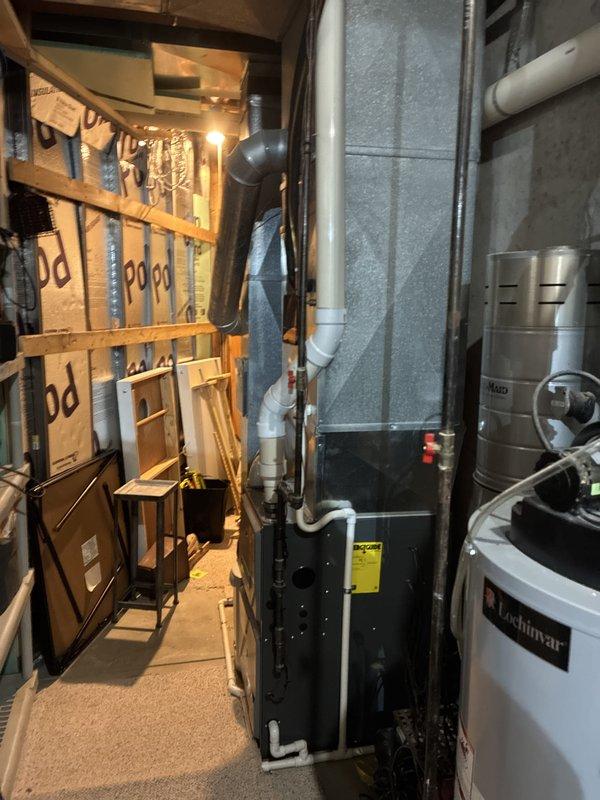 Conducted on-site assessment for air conditioner replacement at residential property. Performed visual inspection of existing HVAC system including gas furnace with exposed internal components showing blower motor assembly, burner elements, and electrical connections. Documented current equipment configuration in basement mechanical room housing furnace unit and water heater with associated ductwork and PVC piping systems to prepare comprehensive replacement estimate.