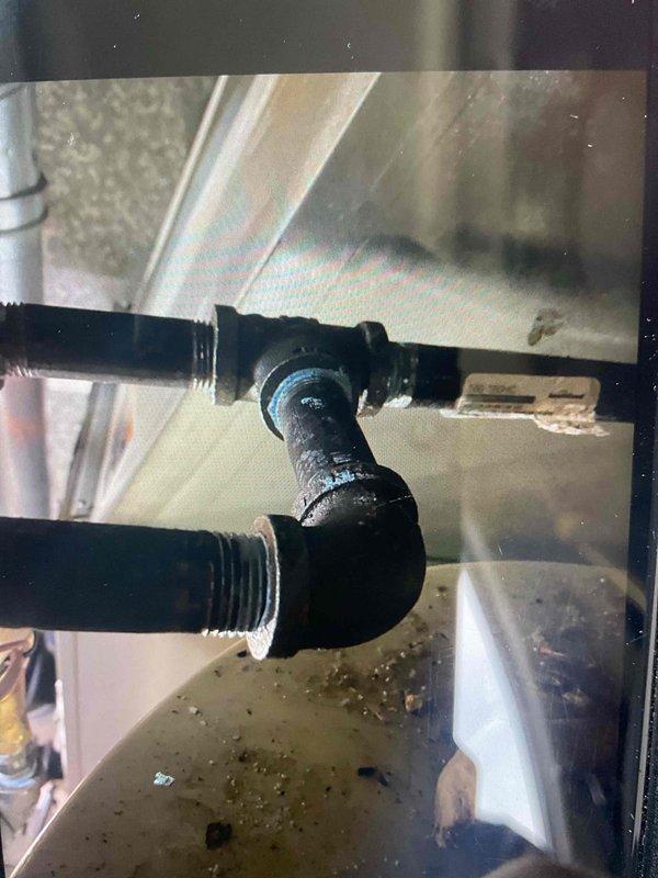 Completed violation repair callback to address gas line code deficiencies identified during initial inspection. Rebuilt gas piping system by installing a proper manifold configuration to serve both the furnace and water heater, ensuring each appliance now has its own dedicated shut-off valve, union, and sediment trap as required by code. Corrected improper sediment trap installation on hot water tank and replaced non-compliant merchant coupling with approved rigid fitting coupling.