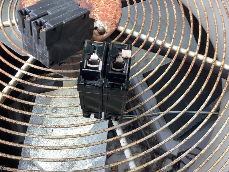 Responded to report of AC breaker tripping repeatedly over a two-day period. Upon inspection, found outdoor condensing unit with 60-amp CU-AL rated circuit breaker and electrical components showing significant weathering, corrosion, and oxidation. Documented condition of contactor, disconnect switch, and wire terminals at top of unit. Extensive rust present on metal fan guard and housing surfaces indicated prolonged environmental exposure. Photographed electrical connections and breaker assembly for service records.