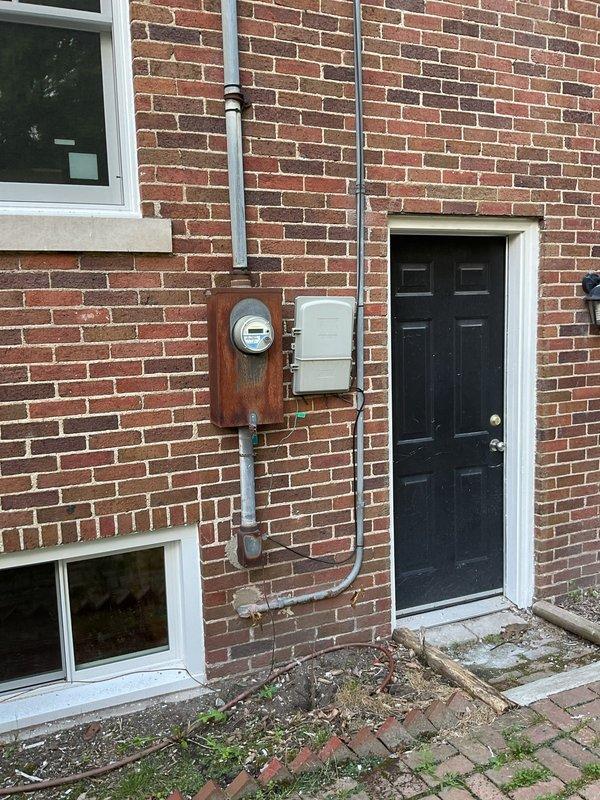 Conducted site assessment for generator installation at approximately 100-year-old residential property. Evaluated existing electrical infrastructure, including aged meter assembly and exterior service equipment mounted on brick exterior. Documented multiple electrical deficiencies requiring attention. Discussed generator options with homeowner, clarifying that only air-cooled units are available through our service offerings. Customer requesting 38KW unit capacity for whole-home backup power solution. Photographed existing electrical service panel, meter base, conduit routing, and proposed generator placement area along side yard near privacy fence. Site presents installation challenges due to age of existing electrical system and will require coordination with utility company for service upgrades to accommodate generator load requirements.